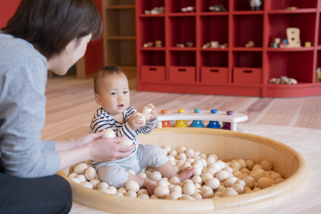 赤ちゃんとその保護者が木製おもちゃで遊んでいる「赤ちゃん木育ひろば」の風景