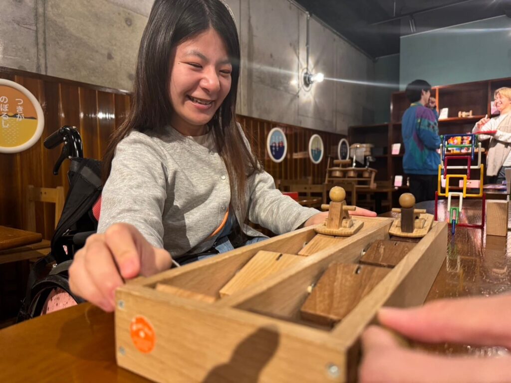 讃岐おもちゃ美術館で学生たちが笑顔で木製おもちゃを使って遊んでいるシーン